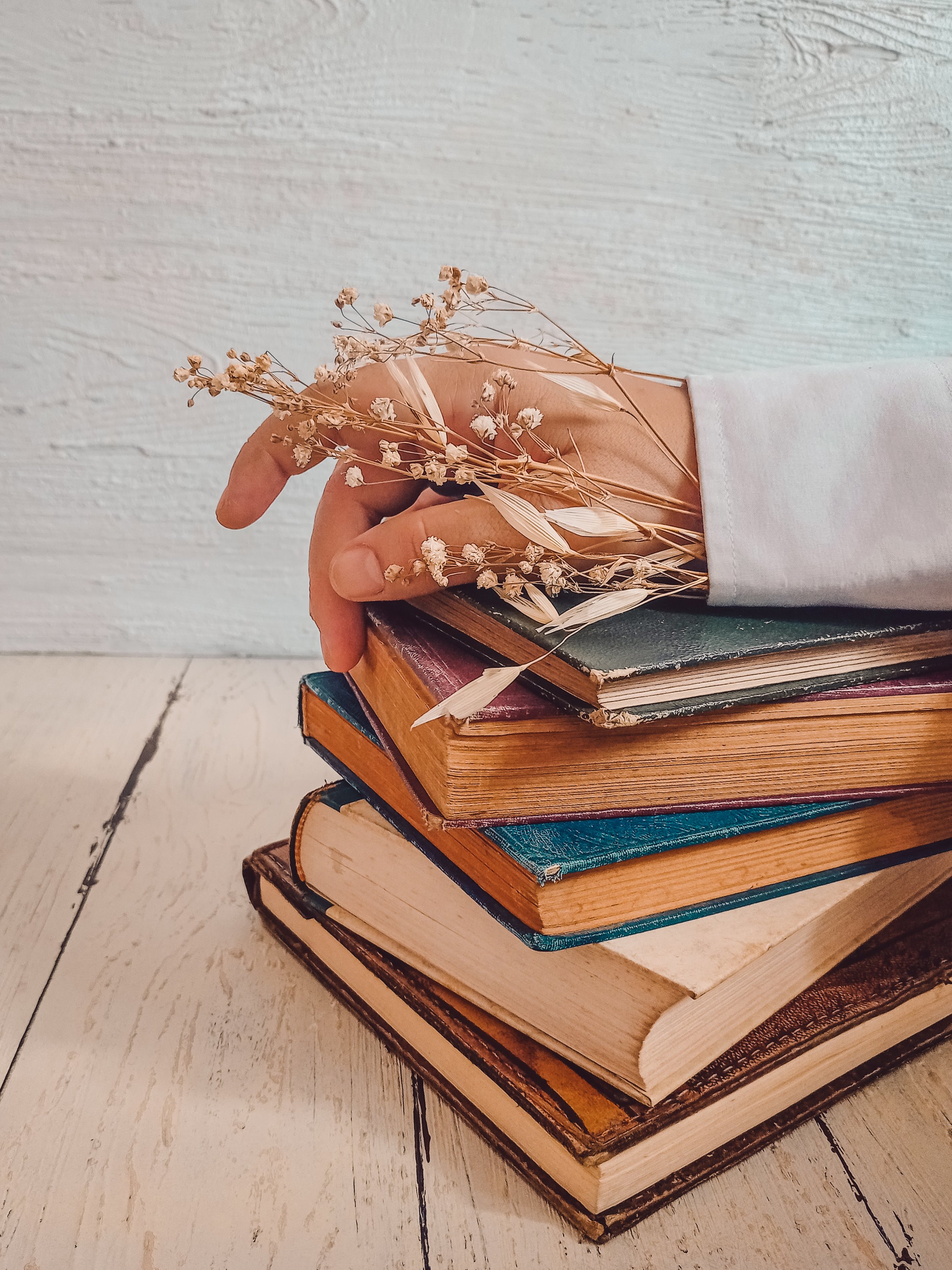 Photo by moldy vintages: https://www.pexels.com/photo/a-person-s-hand-with-dried-flowers-on-top-of-the-stack-of-books-9175042/